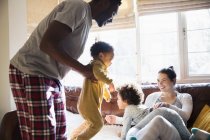 Familia multiétnica juguetona en pijama en la sala de estar - foto de stock