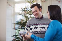 Ehefrau macht Ehemann Weihnachtsgeschenk — Stockfoto