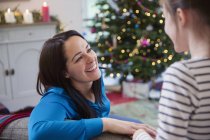 Улыбающаяся мать разговаривает с дочерью в рождественской гостиной — стоковое фото