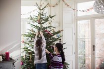 Madre e hija decorando el árbol de Navidad - foto de stock