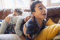 Грайлива, ласкава молода сім'я в піжамі на дивані у вітальні — стокове фото