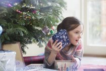 Neugieriges Mädchen schüttelt Weihnachtsgeschenk — Stockfoto