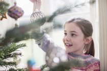 Girl decorating, hanging ornament on Christmas tree — Stock Photo