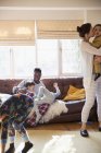 Familia multiétnica juguetona en pijama en la sala de estar soleada - foto de stock