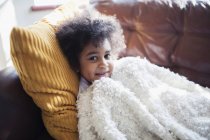 Portrait cute girl relaxing, cuddling on sofa with blanket and pillow — Stock Photo