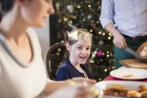 Усміхнена дівчина в паперовій короні на різдвяній вечері — стокове фото