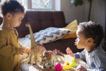 Fratelli bambini che giocano con dinosauri e giocattoli in gomma anatra — Foto stock