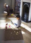 Toddler boy in pajamas playing with toys on living room floor — Stock Photo