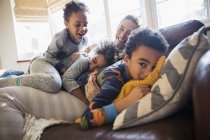 Portrait happy mother and children cuddling on living room sofa — Stock Photo