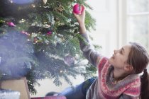 Curieux fille touchant ornement sur arbre de Noël — Photo de stock