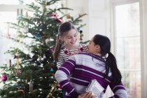 Verspielte Mutter versteckt Weihnachtsgeschenk von Tochter im Wohnzimmer — Stockfoto
