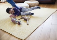 Playful boy with dinosaur toys on living room floor — Stock Photo