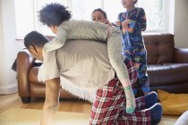 Playful father in pajamas carrying daughter on back — Stock Photo