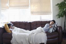 Brother and sister relaxing, watching TV on living room sofa — Stock Photo