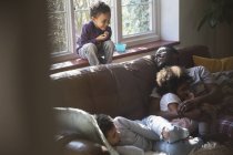 Счастливый отец и дети обнимаются на диване в гостиной — стоковое фото