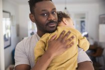 Portrait affectionate father holding tired baby son — Stock Photo