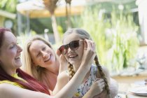 Lesbian couple and daughter playing with sunglasses on patio — Stock Photo