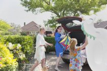Casal de lésbicas e filha carregando unicórnio inflável no hatchback do carro na entrada de casa — Fotografia de Stock
