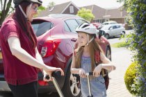 Mother and daughter riding scooters in sunny driveway — Stock Photo