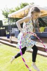 Mädchen spielt mit Plastikreifen im sonnigen Hinterhof — Stockfoto