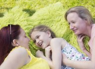 Affectionate lesbian couple and daughter laying in grass — Stock Photo