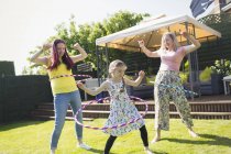 Lesbian couple and daughter playing with plastic hoops in sunny backyard — Stock Photo