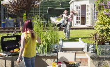 Lesbian couple and daughter playing and barbecuing in sunny backyard — Stock Photo