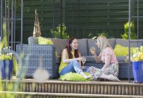 Feliz pareja lesbiana bebiendo vino blanco, relajándose en el patio - foto de stock