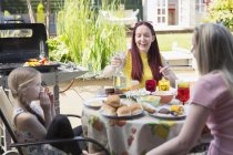 Lesbian couple and daughter enjoying lunch at patio table — Stock Photo