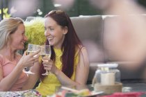 Cariñosa lesbiana pareja bebiendo blanco vino en patio - foto de stock