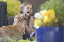 Dog kissing laughing girl on patio — Stock Photo