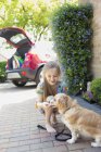 Girl giving treat to dog in driveway — Stock Photo