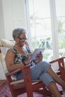 Старша жінка використовує цифровий планшет у кріслі для камінгу — стокове фото