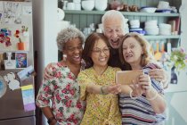 Happy, playful active seniors taking selfie with camera phone, making silly faces — Stock Photo