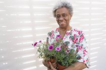 Ritratto sorridente, fiduciosa donna anziana attiva giardinaggio, tenendo vasi da fiori — Foto stock