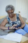 Старшая женщина с калькулятором рассматривает счета — стоковое фото