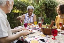 Amici anziani che si godono il pranzo al tavolo patio — Foto stock