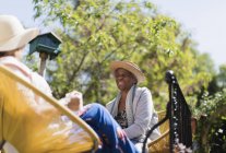 Счастливые пожилые подруги разговаривают на солнечном дворике — стоковое фото