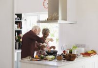 Активная пара пожилых людей приготовление пищи на кухне — стоковое фото