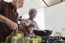 Active senior couple cooking in kitchen — Stock Photo