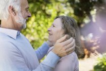 Cariñosa pareja de ancianos abrazándose en el jardín - foto de stock