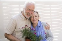 Portrait happy active senior couple with flowerpots — Stock Photo