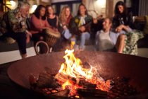 Friends hanging out, playing music on patio next to fire pit — Stock Photo