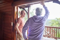 Father and son talking at cabin patio doorway — Stock Photo