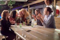 Happy friends clapping, celebrating on patio at night — Stock Photo
