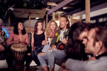 Friends hanging out, playing music on patio at night — Stock Photo