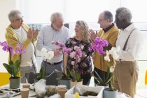 Активні старші чоловіки плескають для інструктора жіночої статі в класі квіткових композицій — стокове фото