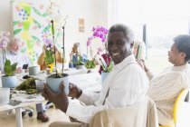 Портрет впевнений активний старший чоловік насолоджується класом квіткових композицій — стокове фото
