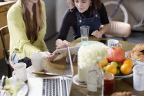 Young women roommate friends using digital tablet at breakfast table — Stock Photo