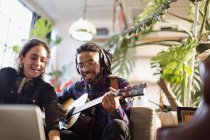 Young man and woman recording music, playing guitar in apartment — Stock Photo